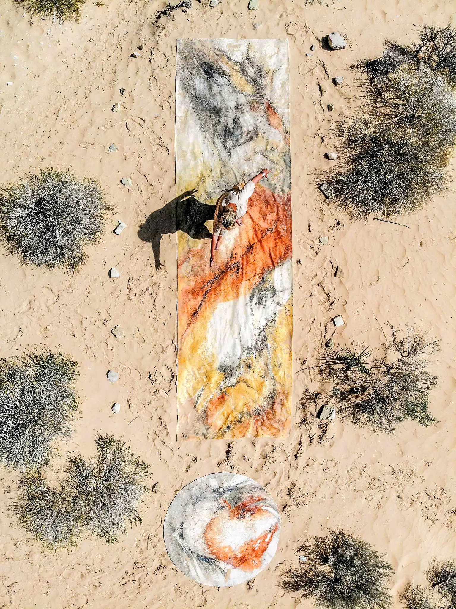 Ulrike standing on the canvas, while painting with earth.